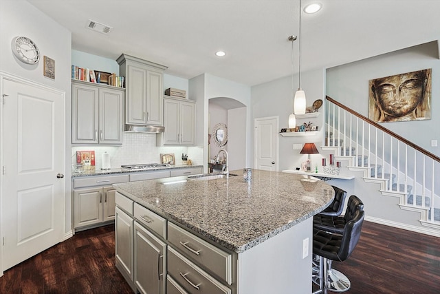 kitchen with sink, stainless steel gas stovetop, gray cabinetry, and a kitchen island with sink