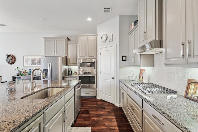 kitchen with sink, dark hardwood / wood-style floors, light stone counters, and appliances with stainless steel finishes