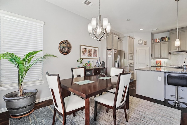 dining space featuring sink, a notable chandelier, and dark wood-type flooring