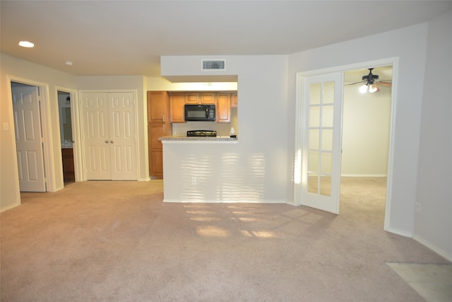 unfurnished living room with light carpet, french doors, and ceiling fan