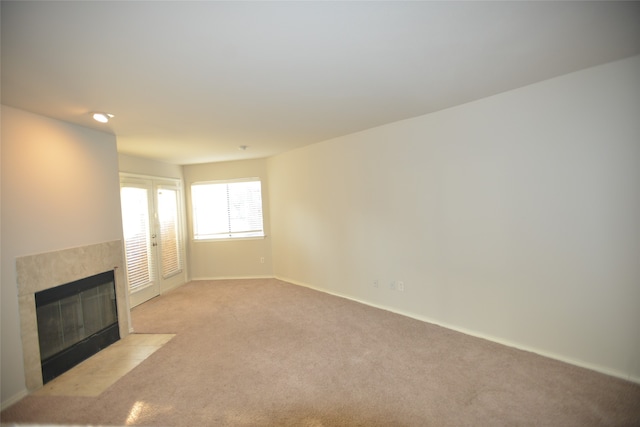 unfurnished living room with light carpet and a tile fireplace