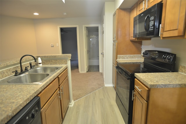 kitchen with light hardwood / wood-style floors, black appliances, and sink