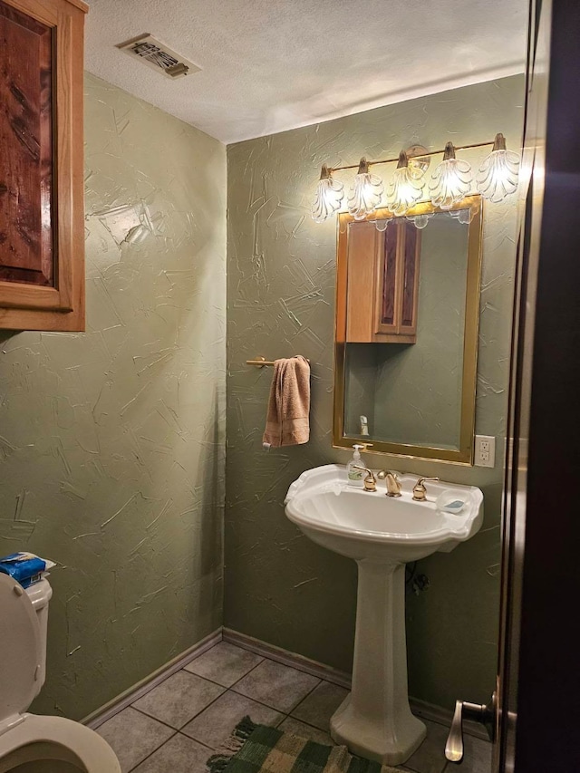 bathroom with toilet, tile patterned floors, and a textured ceiling