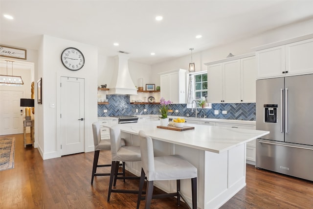 kitchen with white cabinetry, dark hardwood / wood-style floors, a kitchen island, custom range hood, and appliances with stainless steel finishes