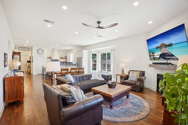 living room featuring ceiling fan and dark hardwood / wood-style floors