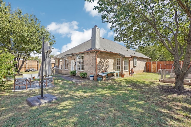 back of house with a lawn and a patio