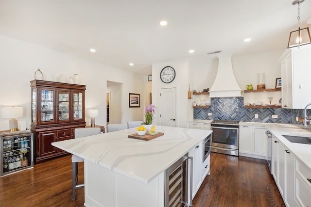 kitchen with beverage cooler, dark hardwood / wood-style flooring, pendant lighting, a kitchen island, and appliances with stainless steel finishes