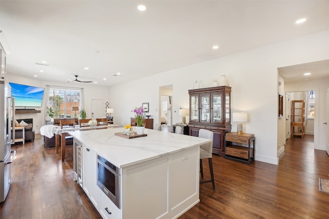 kitchen featuring a kitchen breakfast bar, dark hardwood / wood-style flooring, white cabinetry, and a kitchen island