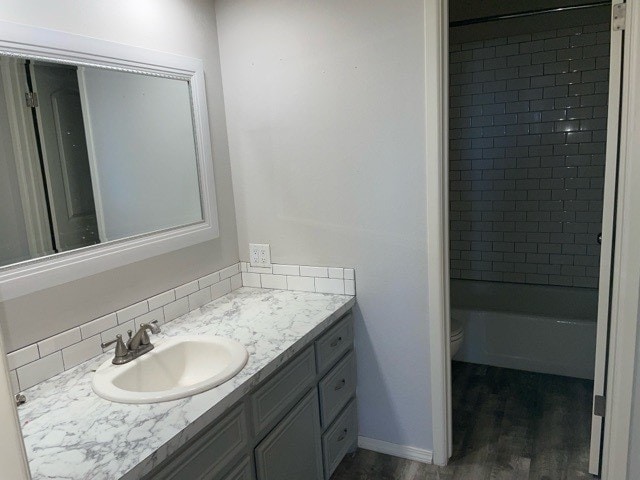 full bathroom featuring vanity, toilet, hardwood / wood-style flooring, and tiled shower / bath combo