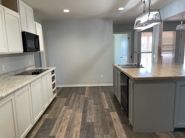 kitchen with dark hardwood / wood-style flooring, white cabinetry, black appliances, wooden counters, and sink