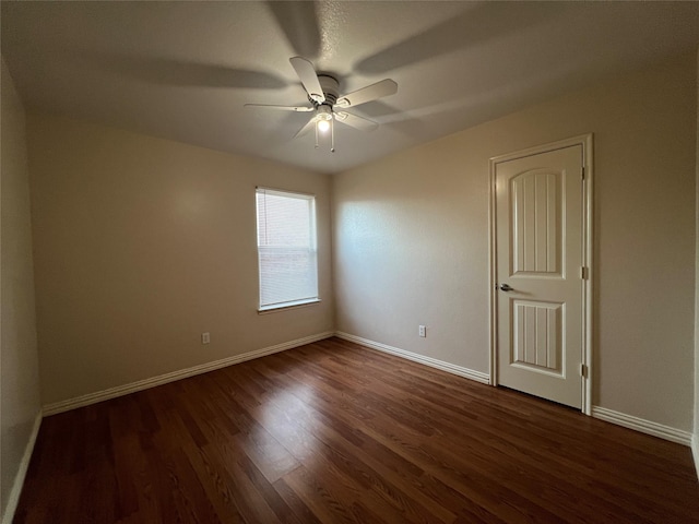 empty room with ceiling fan and dark hardwood / wood-style flooring