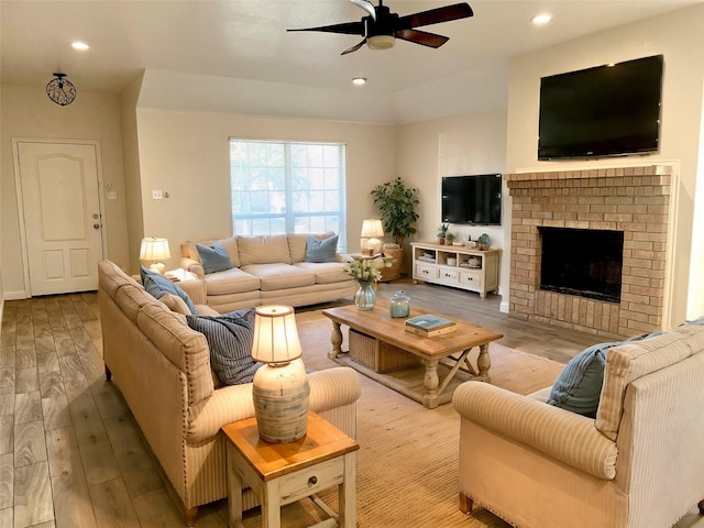 living room with hardwood / wood-style floors, ceiling fan, and a fireplace