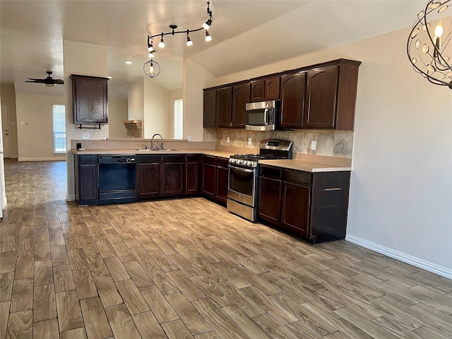 kitchen with ceiling fan with notable chandelier, sink, hanging light fixtures, vaulted ceiling, and stainless steel appliances