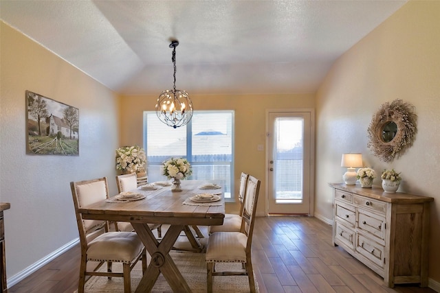 dining room with lofted ceiling, hardwood / wood-style flooring, a textured ceiling, and an inviting chandelier