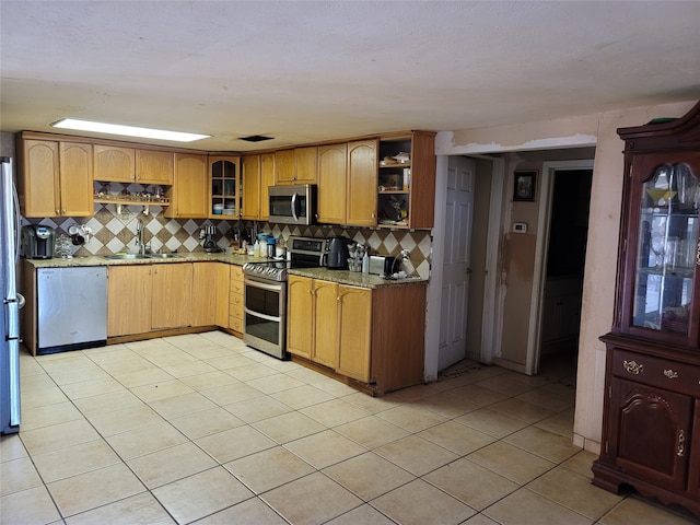 kitchen with light stone counters, stainless steel appliances, sink, and light tile patterned flooring