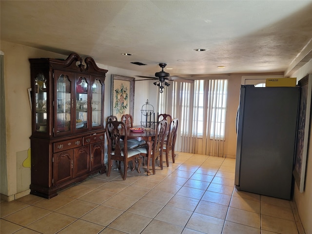 tiled dining area with a textured ceiling and ceiling fan