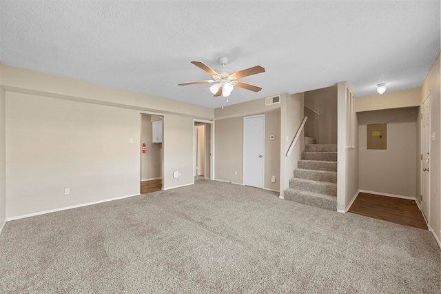 interior space featuring ceiling fan, electric panel, a textured ceiling, and carpet floors