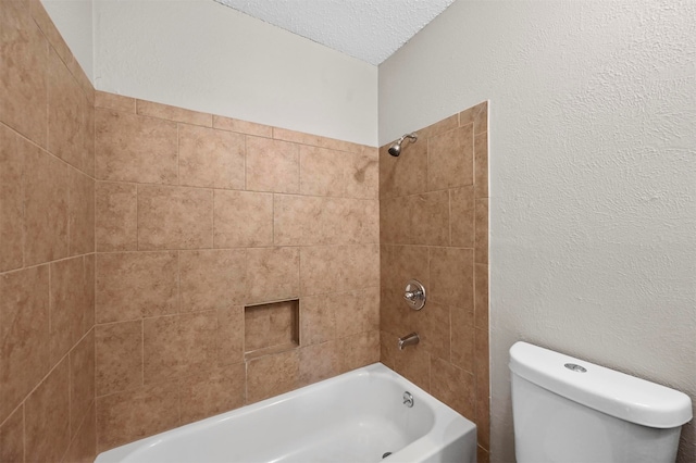 bathroom featuring toilet, a textured ceiling, and tiled shower / bath