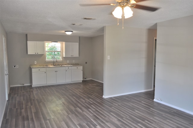 kitchen with white cabinetry, sink, dark wood-type flooring, and a textured ceiling