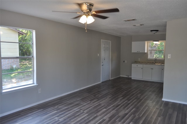 unfurnished living room featuring a textured ceiling, dark hardwood / wood-style floors, sink, and ceiling fan