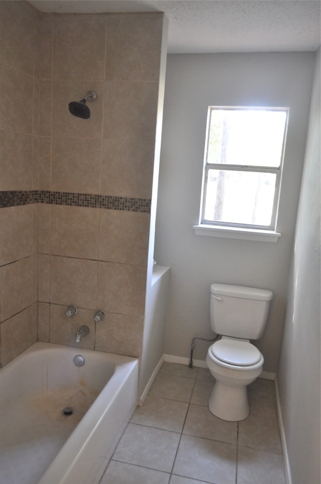 bathroom featuring tiled shower / bath, a textured ceiling, toilet, and tile patterned flooring