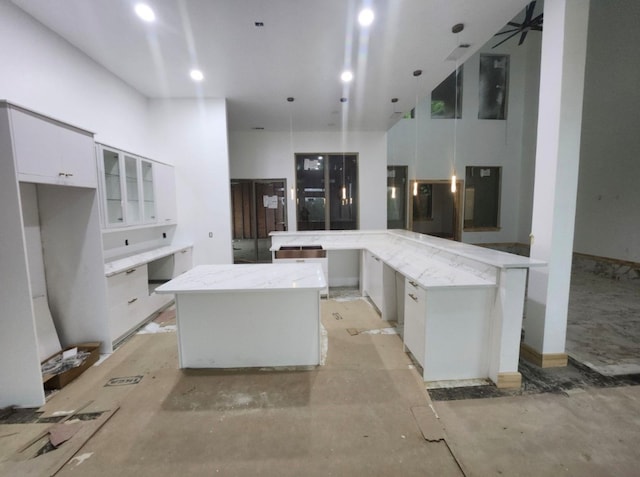 kitchen with ceiling fan, kitchen peninsula, a kitchen island, and white cabinets