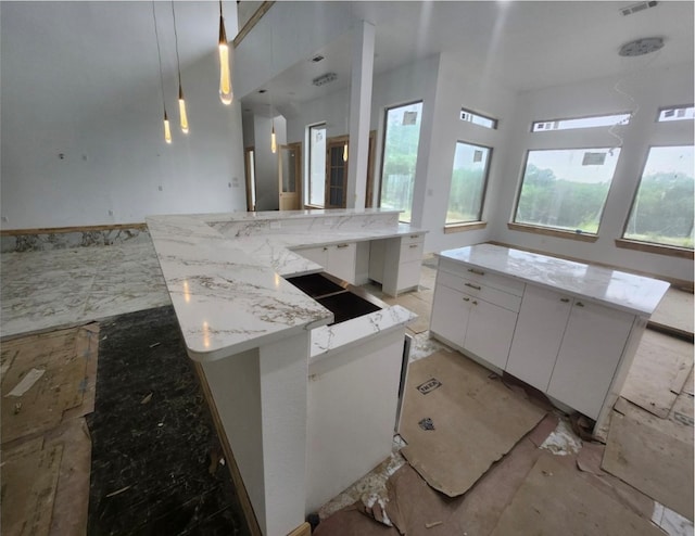 kitchen featuring a large island, white cabinetry, light stone countertops, and hanging light fixtures