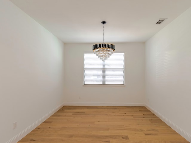 unfurnished room with an inviting chandelier and light wood-type flooring