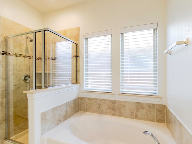 bathroom featuring plenty of natural light and separate shower and tub