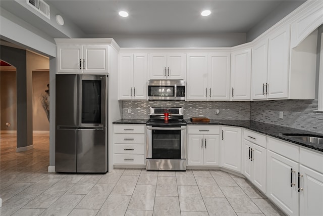 kitchen with white cabinetry, stainless steel appliances, and backsplash