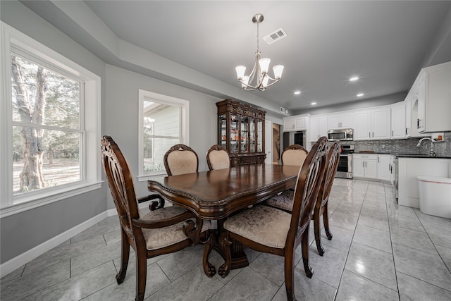 dining area with light tile patterned floors, a notable chandelier, and sink