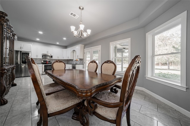 dining space with light tile patterned floors and ceiling fan with notable chandelier