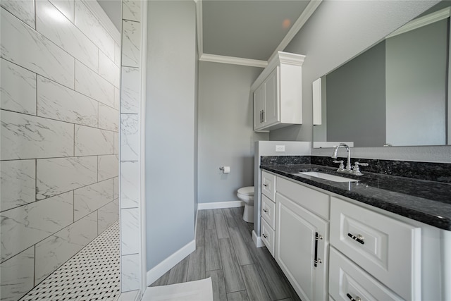 bathroom featuring vanity, toilet, crown molding, and a tile shower