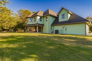 back of property with a yard and central AC unit