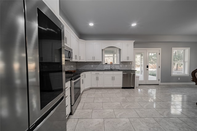 kitchen featuring white cabinets, tasteful backsplash, light tile patterned flooring, sink, and stainless steel appliances