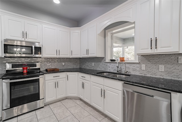 kitchen featuring sink, white cabinetry, stainless steel appliances, and dark stone countertops