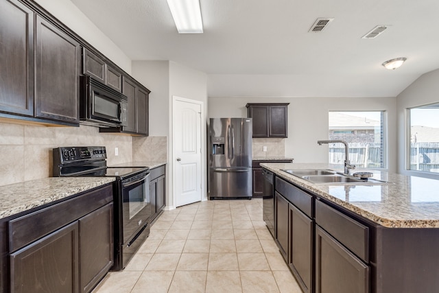 kitchen with a kitchen island with sink, backsplash, sink, black appliances, and light tile patterned flooring