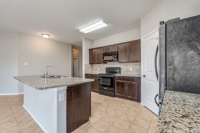 kitchen with decorative backsplash, a center island with sink, black appliances, dark brown cabinetry, and sink