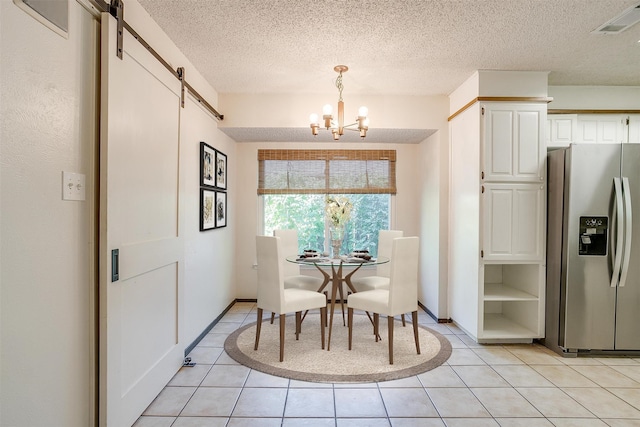 dining area featuring a textured ceiling, an inviting chandelier, light tile patterned floors, and a barn door