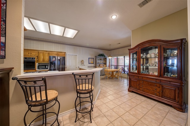 kitchen with kitchen peninsula, stainless steel fridge, crown molding, oven, and a breakfast bar area