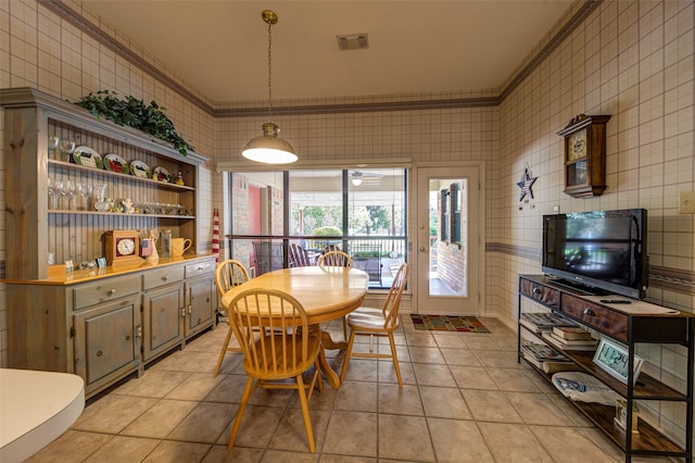 dining room with light tile patterned floors, tile walls, and ornamental molding