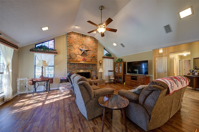 living room featuring a brick fireplace, a textured ceiling, vaulted ceiling, ceiling fan, and wood-type flooring