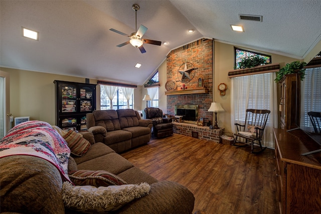 living room with ceiling fan, a brick fireplace, hardwood / wood-style floors, a textured ceiling, and vaulted ceiling