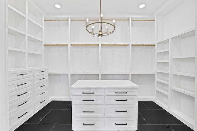 walk in closet with dark tile patterned floors and a notable chandelier