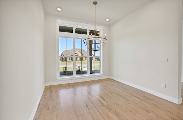 unfurnished dining area with light wood-type flooring and a chandelier