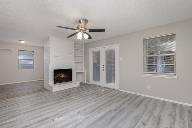 509 Ridgeview Dr, Rockwall, TX 75087 - unfurnished living room with a textured ceiling, light wood-style floors, a fireplace, built in features, and baseboards