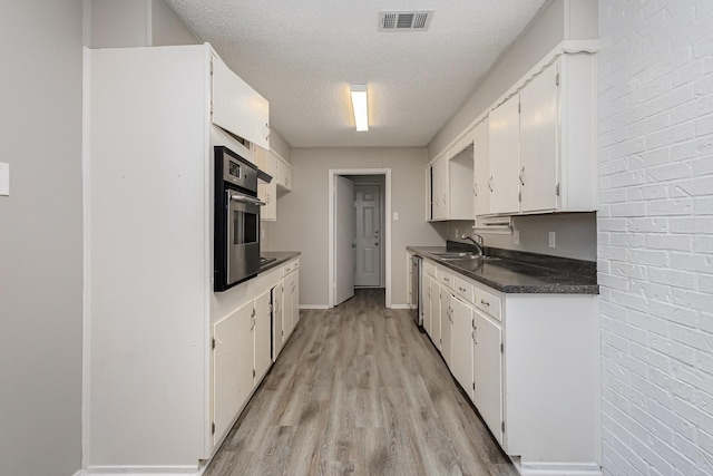509 Ridgeview Dr, Rockwall, TX 75087 - kitchen featuring stainless steel appliances, a sink, dark countertops, a textured ceiling, and light wood-type flooring