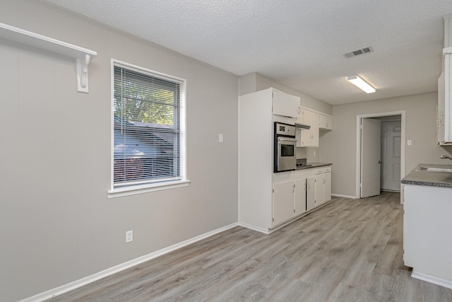 509 Ridgeview Dr, Rockwall, TX 75087 - kitchen featuring a sink, stainless steel oven, a textured ceiling, light wood-type flooring, and dark countertops