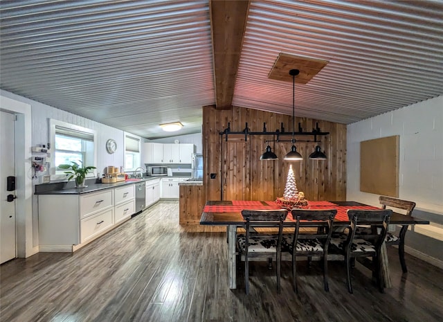 dining area with lofted ceiling with beams, wooden walls, and dark wood-type flooring