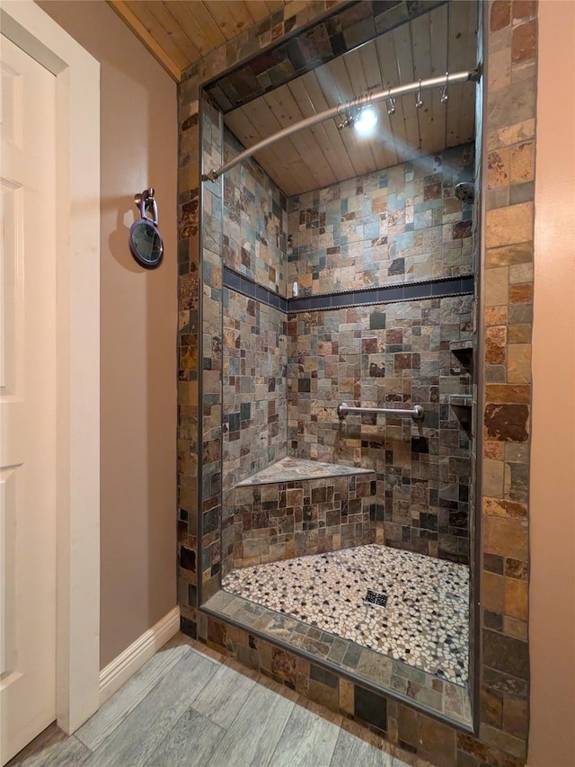 bathroom with wood ceiling, hardwood / wood-style flooring, and tiled shower